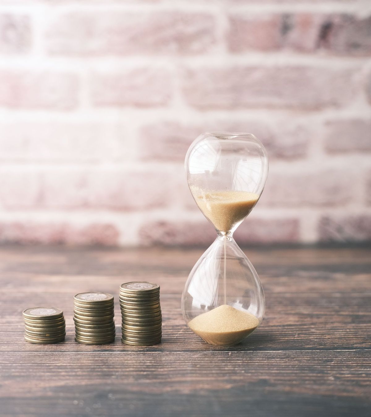 An hourglass beside a small stack of coins